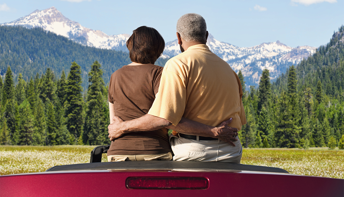 couple sitting in convertible looking at mountains 