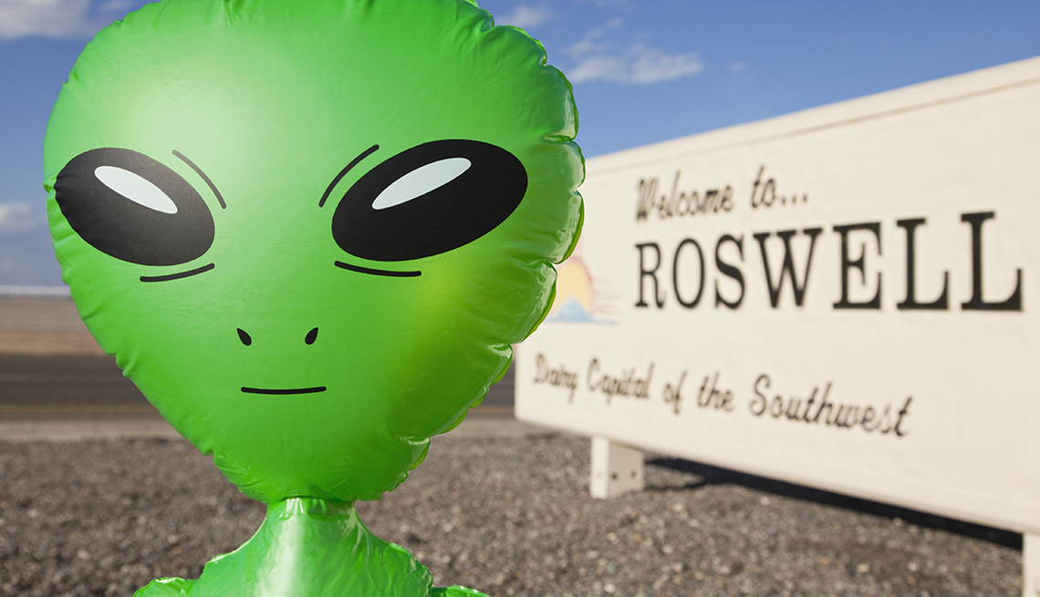 Blow Up Alien Doll Outside A Sign Welcoming Visitors To Roswell New Mexico, Strange Destinations