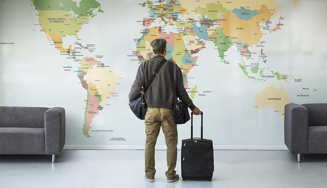 Hombre que viaja mira un mapa del mundo en una pared