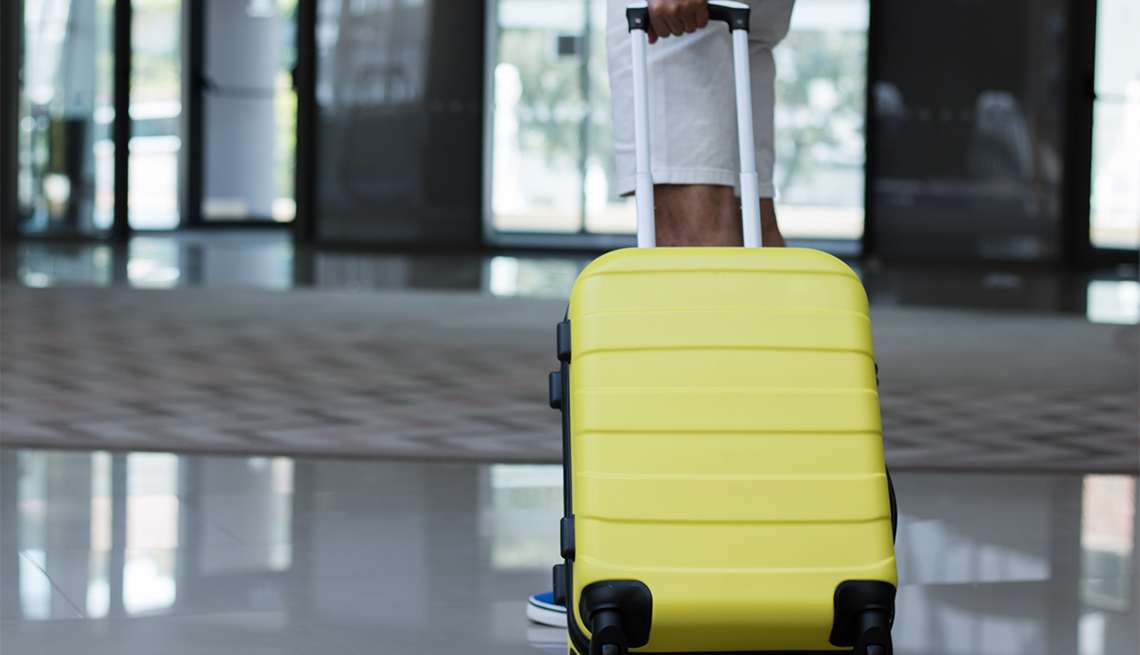 Persona con maleta amarilla esperando en el pasillo de un hotel