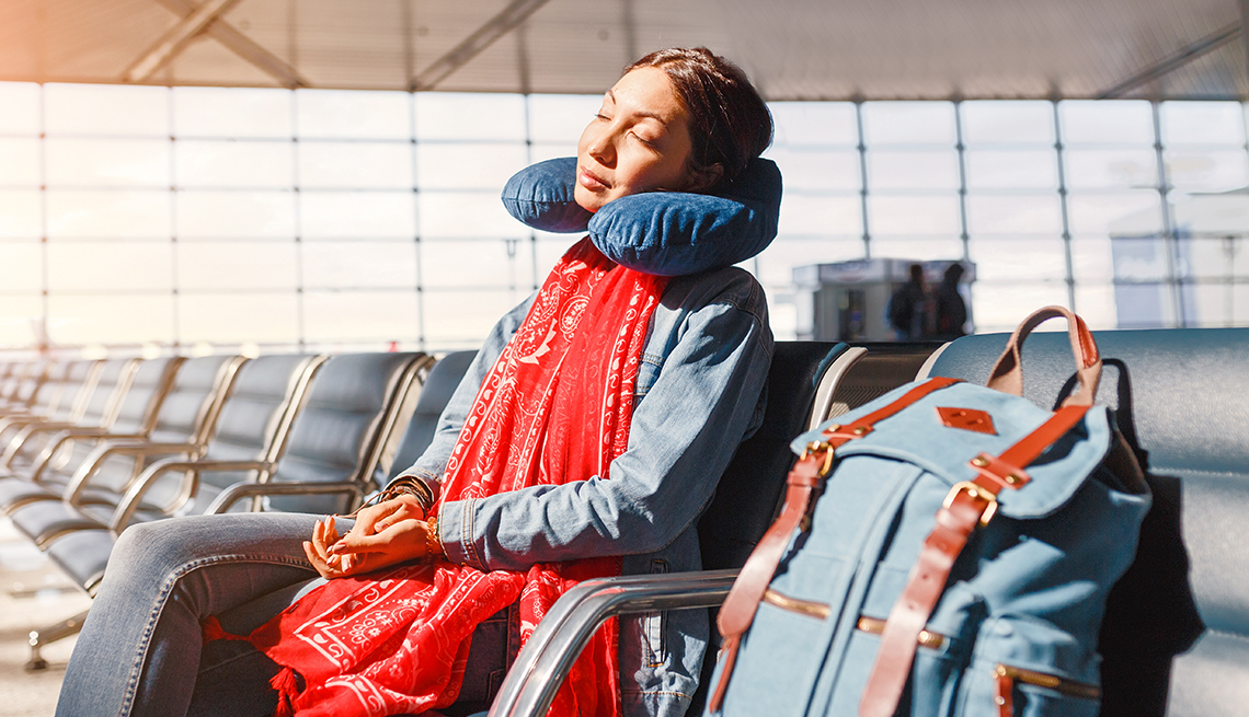 Mujer en el aeropuerto descansando en una sala de espera con una almohada para el cuello