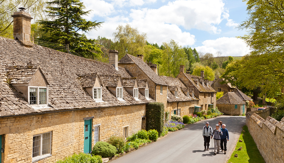 Hikers enjoying the stone cottages beside the lane in the Cotswold village of Snowshill, Gloucestershire UK