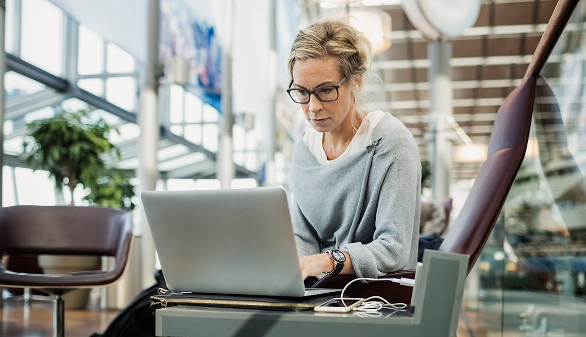 Mujer viendo pantalla de computadora - Maneras de conseguir pasajes aéreos baratos