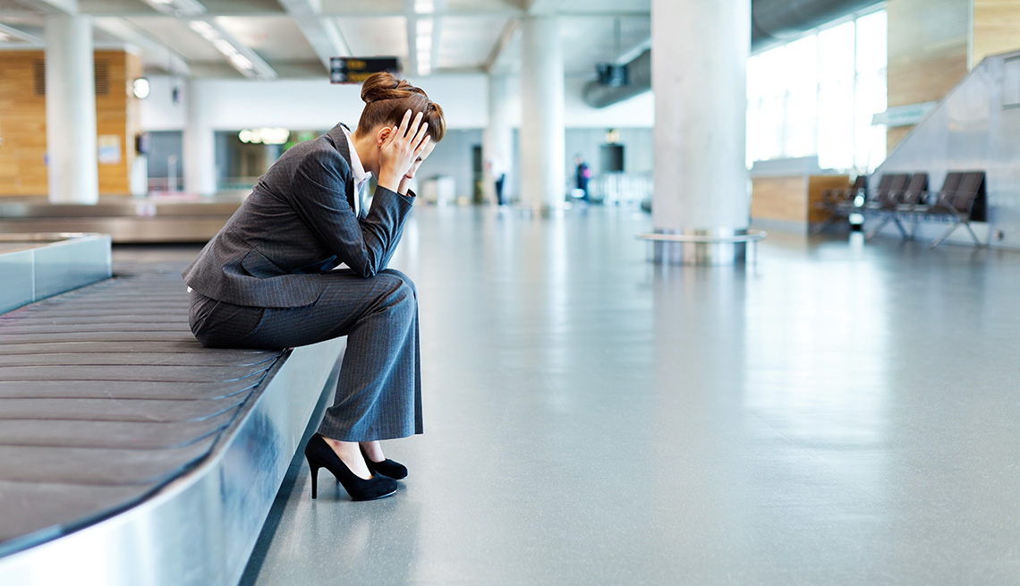 worried woman waiting for luggage at airport baggage claim