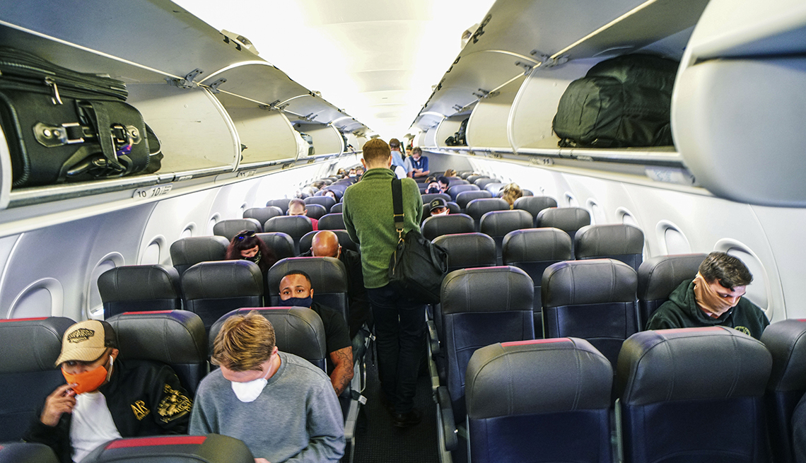 looking down the center aisle of a mostly empty airplane being boarded during the coronavirus pandemic