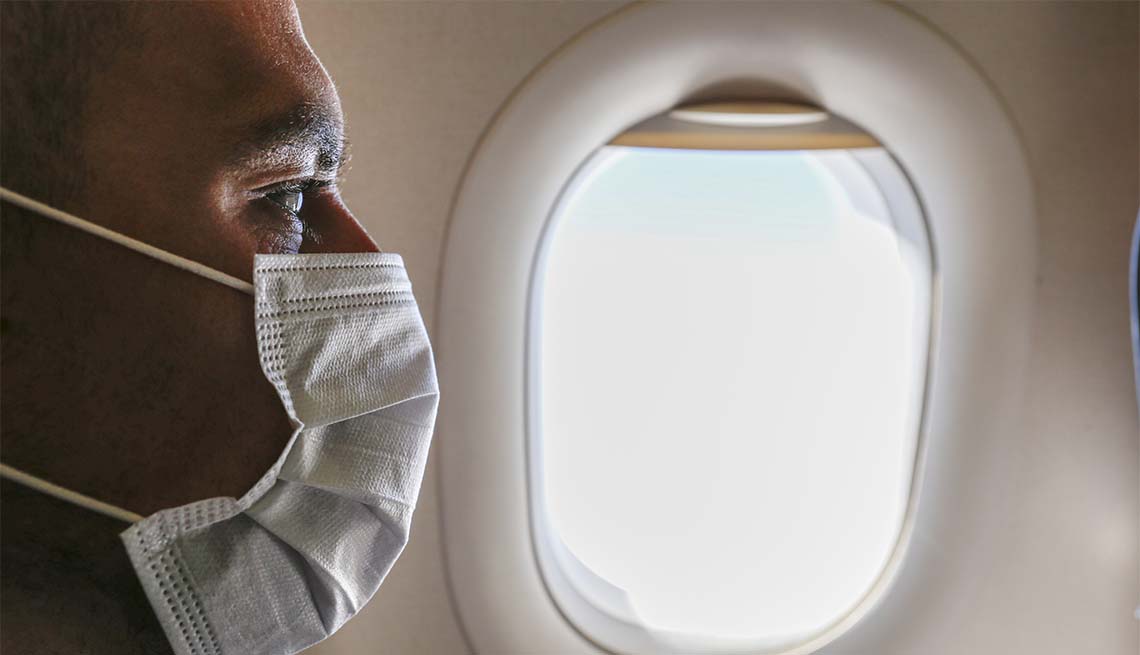 Un hombre lleva puesta una mascarilla dentro de un avión