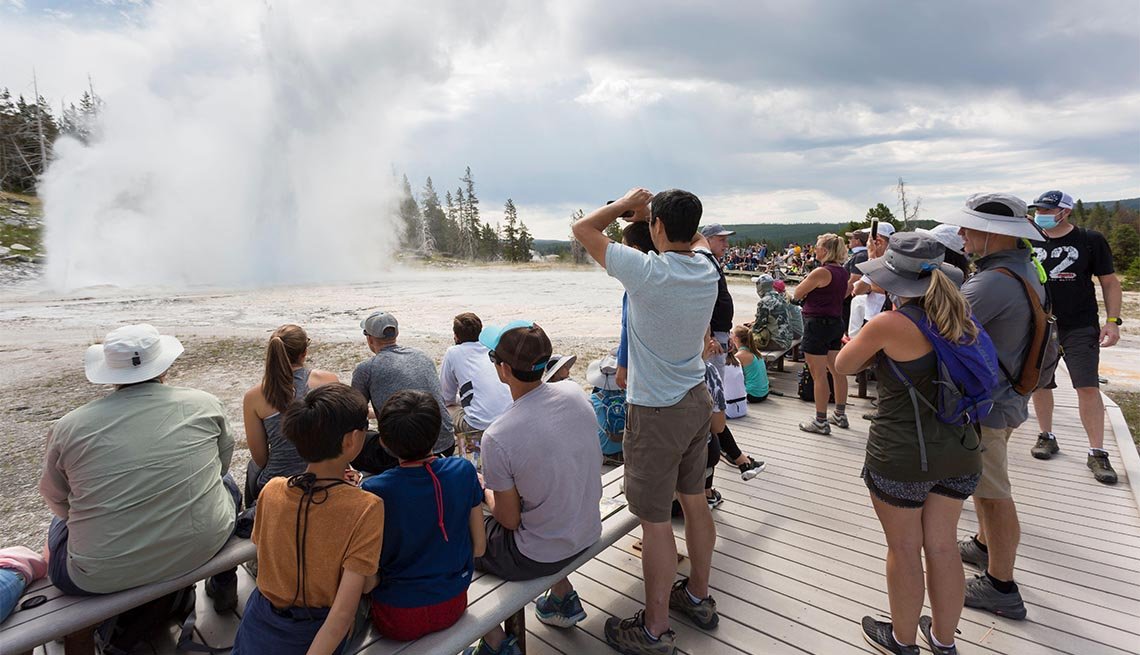 Visitors crowd the boardwalk as Grand Geyser erupts in Yellowstone National Park