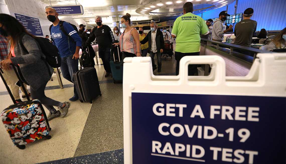 Arriving travelers walk past a sign directing them to get a free COVID-19 Rapid Test at the Tom Bradley International Terminal