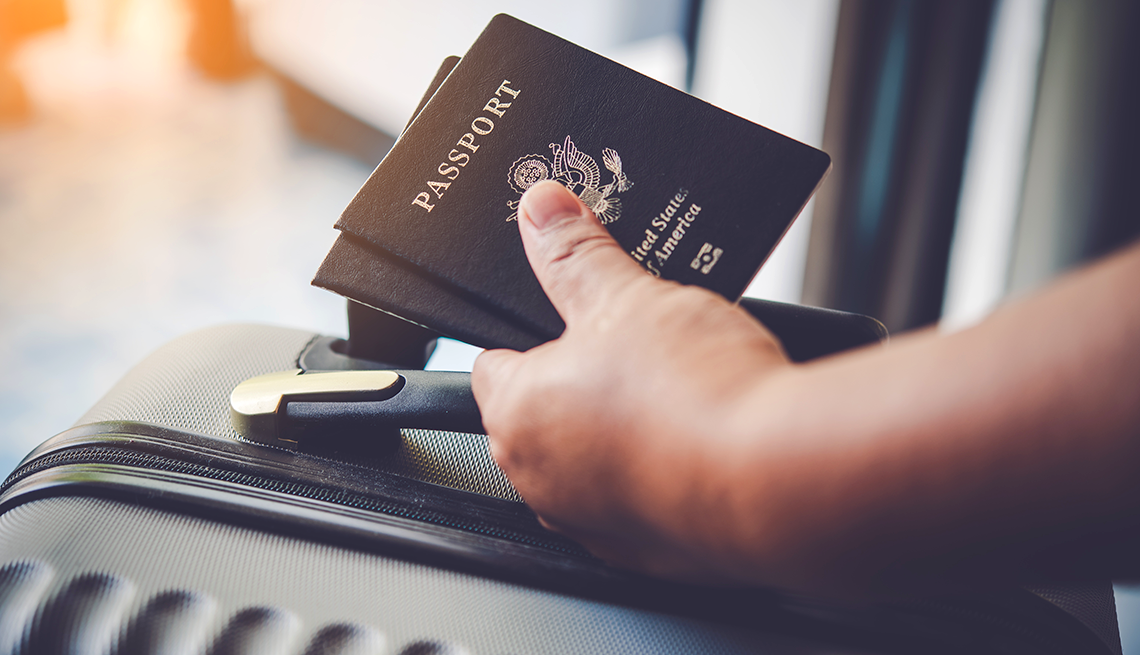 Persona lleva en la mano su equipaje de mano y pasaportes