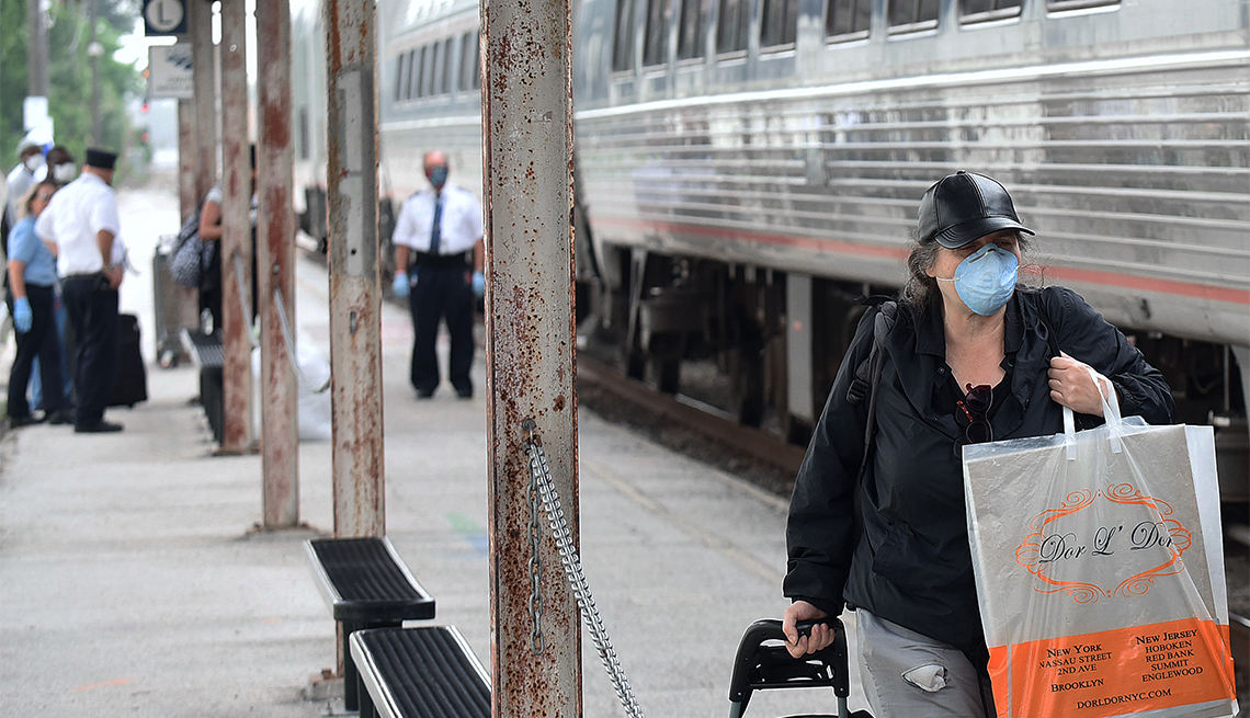 Mujer lleva puesta una máscara mientras pasa junto a un tren Amtrak