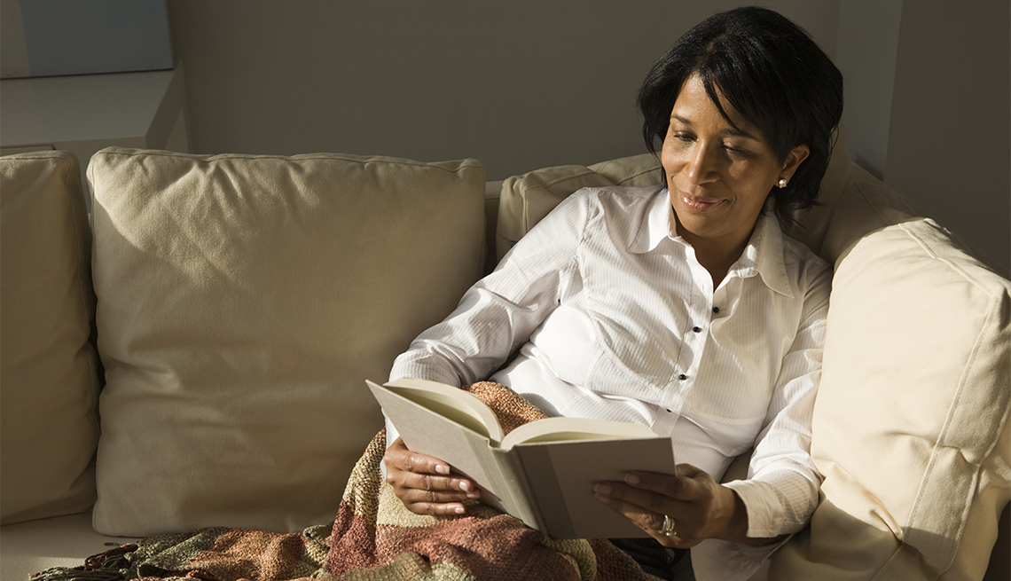 Mujer sentada en un sofá lee un libro