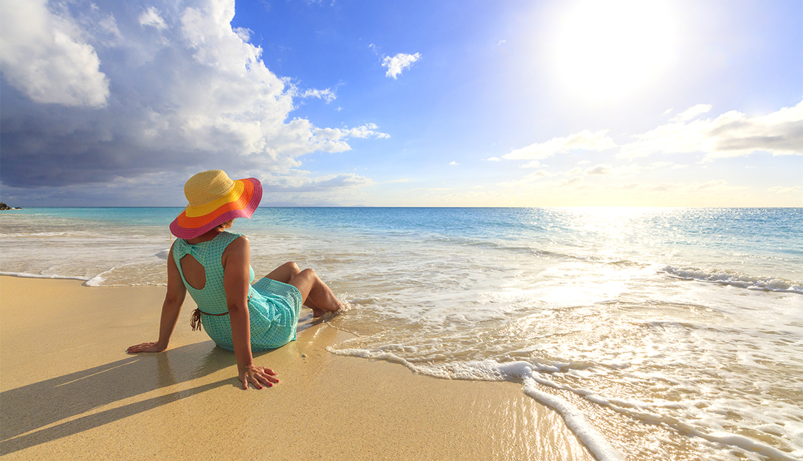 Mujer con sombrero sentada en la orilla del mar en Antigua