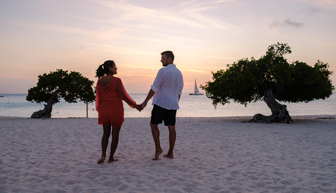 a couple holding hands while on the beach in Aruba