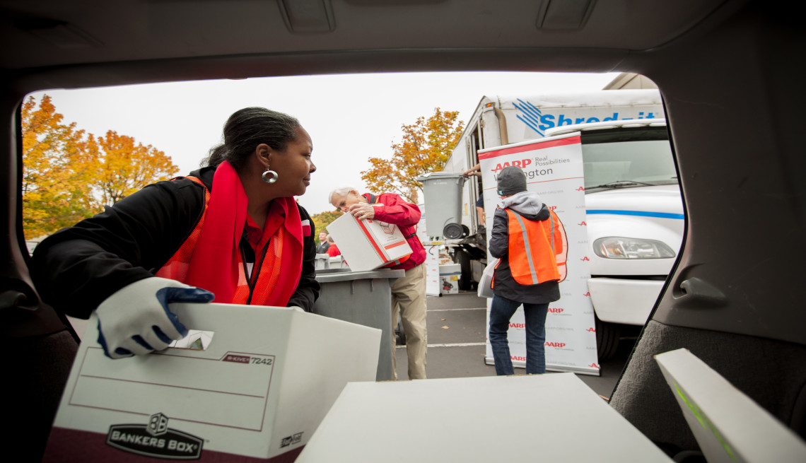 A female volunteer moving out paper boxes from a van at a shred event