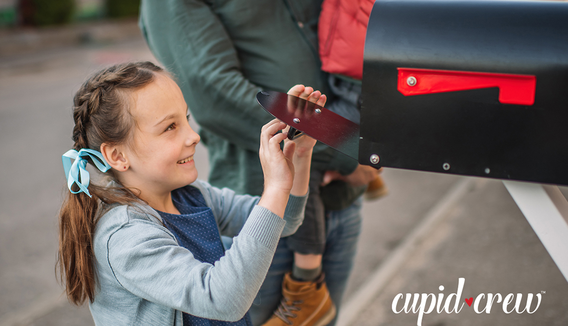 a young girl is placing something inside of a mailbox