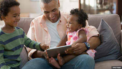 Padre y sus hijos en un sofá, beneficios del Seguro Social para los niños