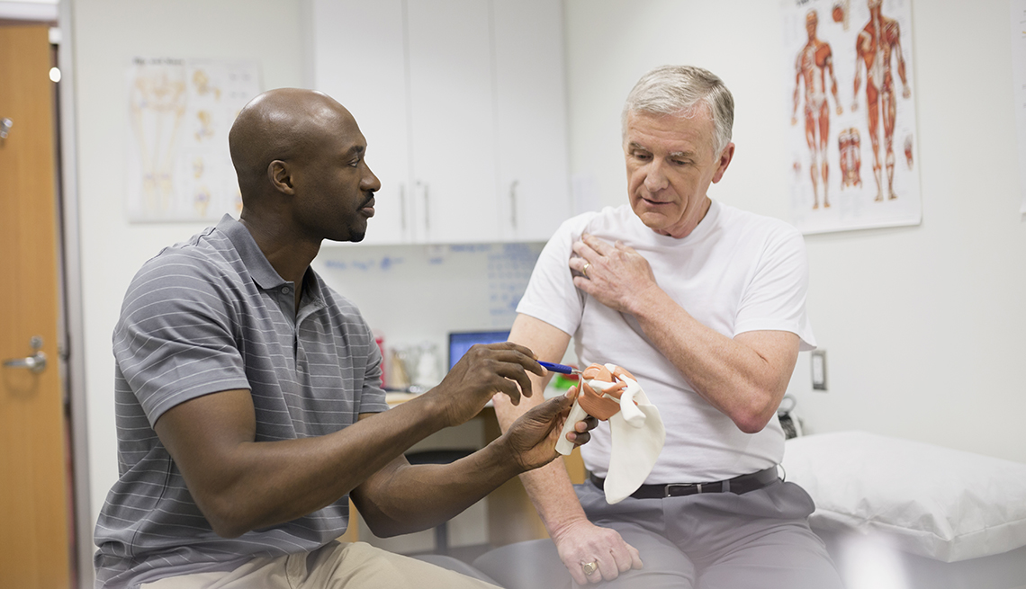 A male physical therapist treats a male patient with shoulder pain
