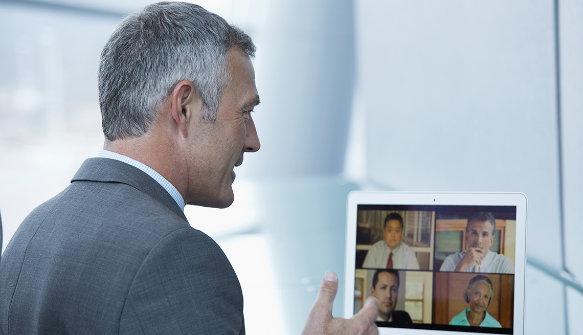 Hombre en traje de corbata desde su casa y haciendo una videoconferencia con otros colegas.