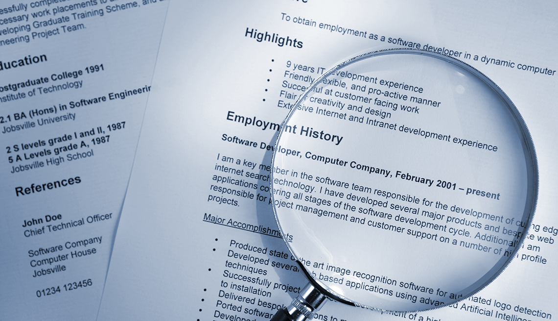 A resume with a magnifying glass on top of it