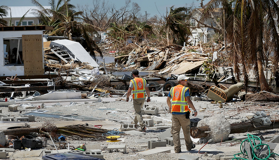 Hombres caminando por escombros dejados por el paso del huracán y los empleos a los que podrían aplicar las personas mayores.