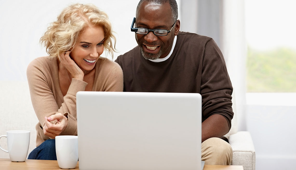 Mujer y hombre viendo una computadora personal encima de una mesa de sala