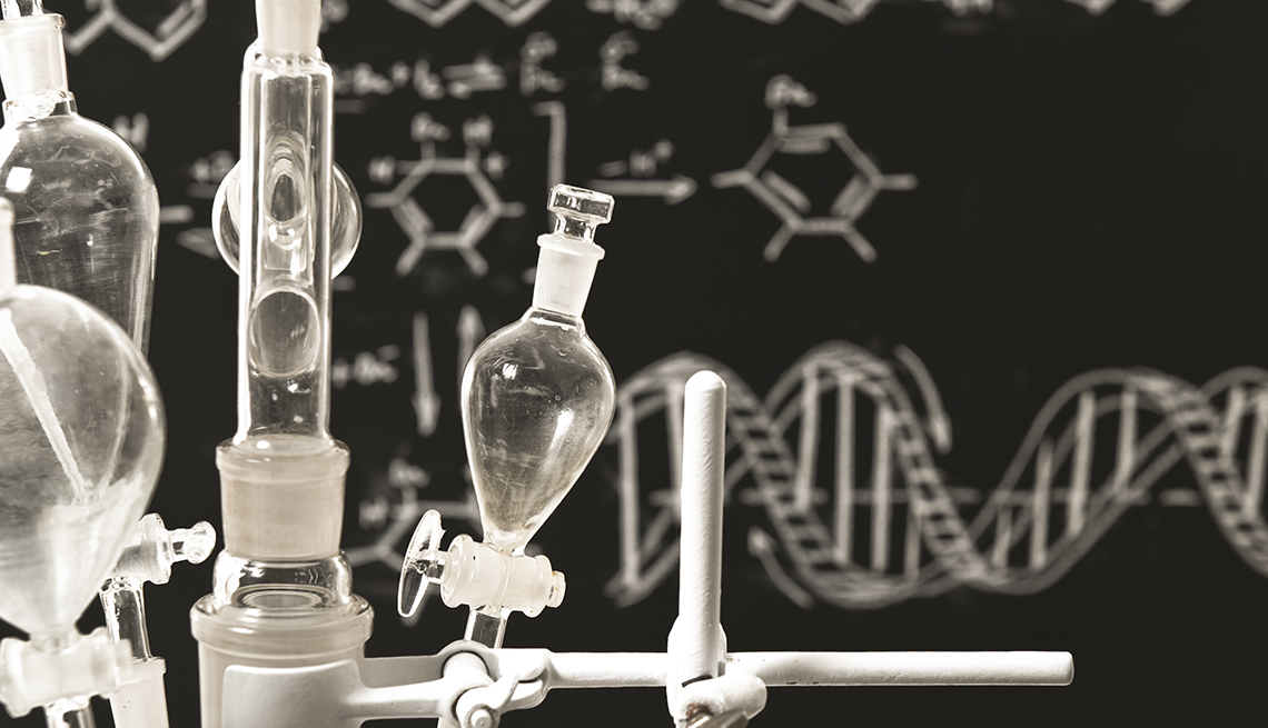 Instrumentos de un laboratorio y detrás estructuras químicas dibujadas sobre un tablero negro