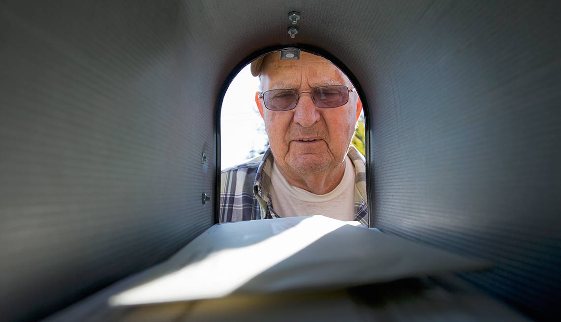 Hombre mayor mirando un buzón de correo