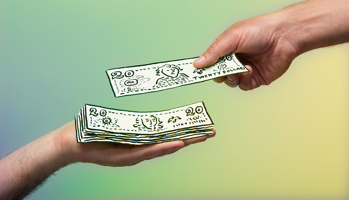Dos manos sosteniendo billetes de dólar de juguete