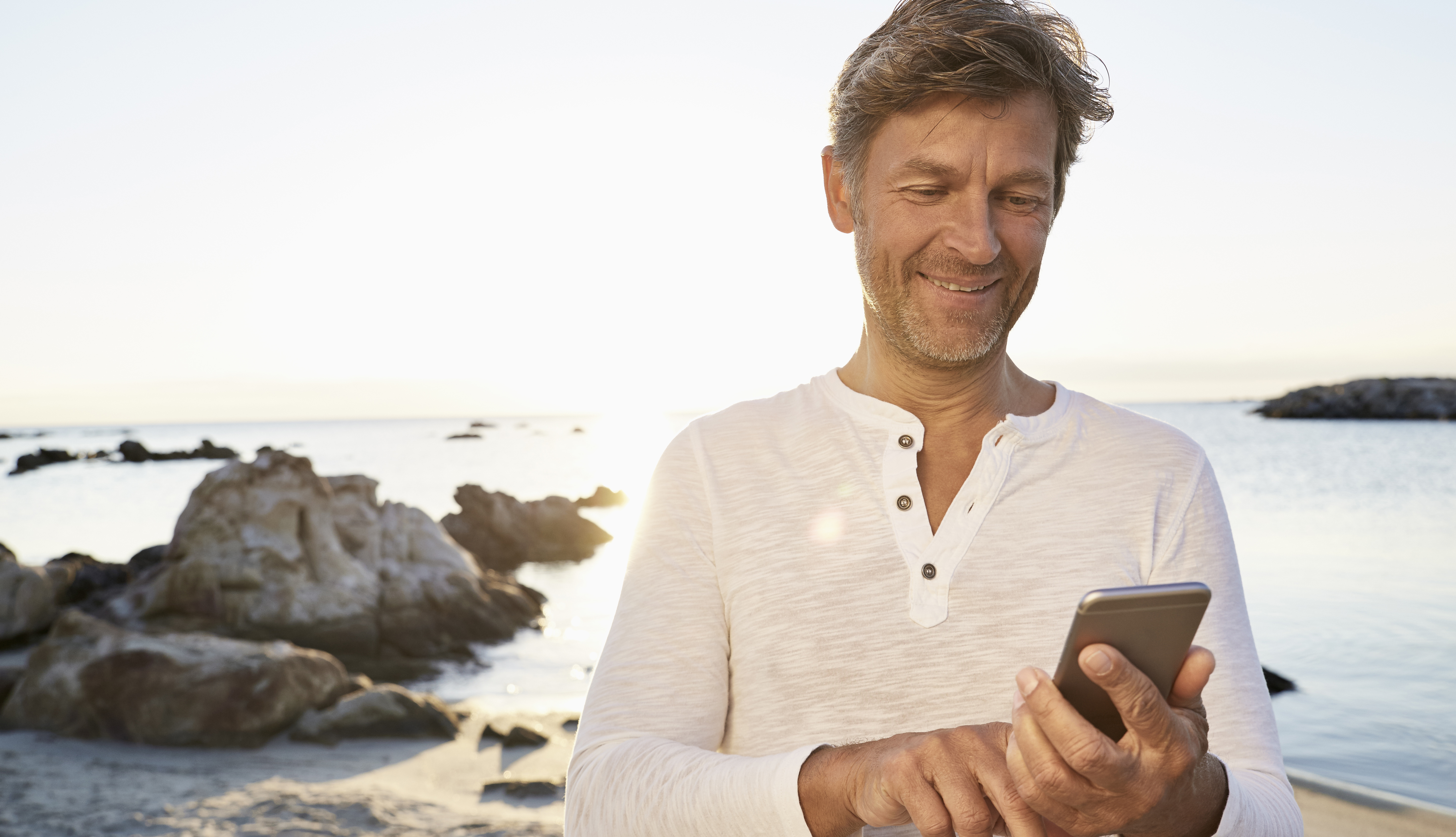man using smartphone on beach
