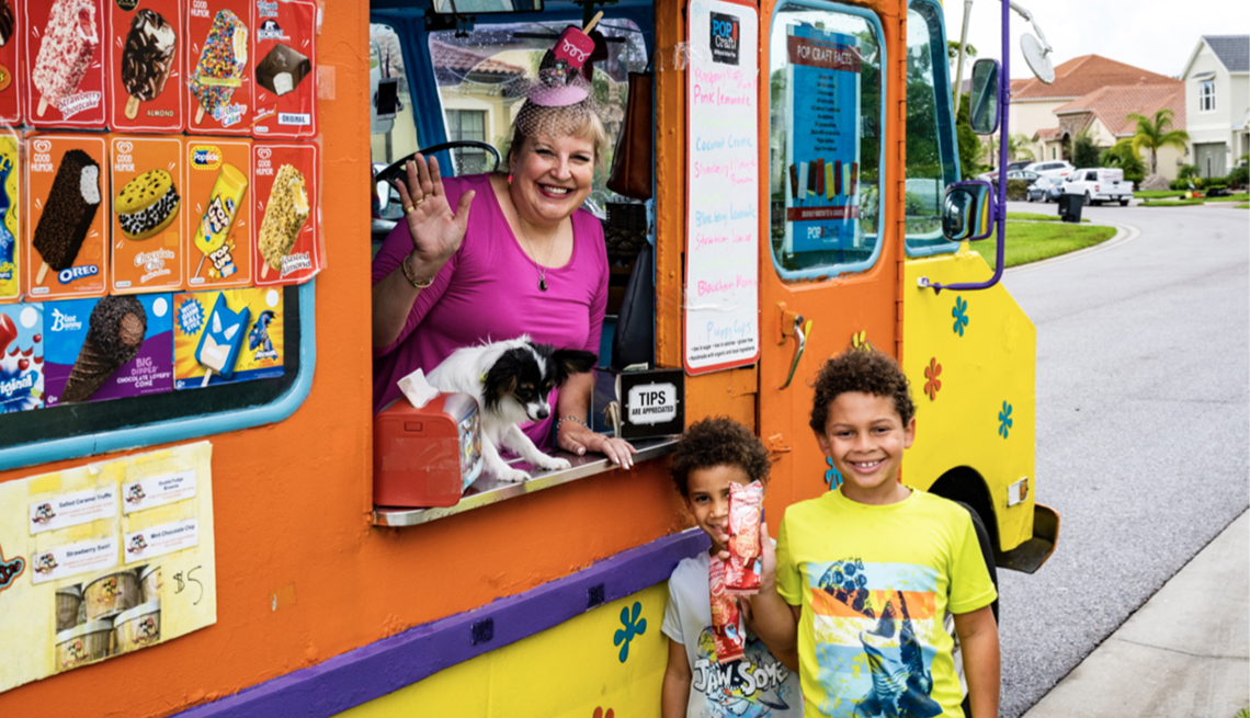 tammy hauser waves from her ice cream truck along with her dog and two kids out in front of the truck with their ice cream