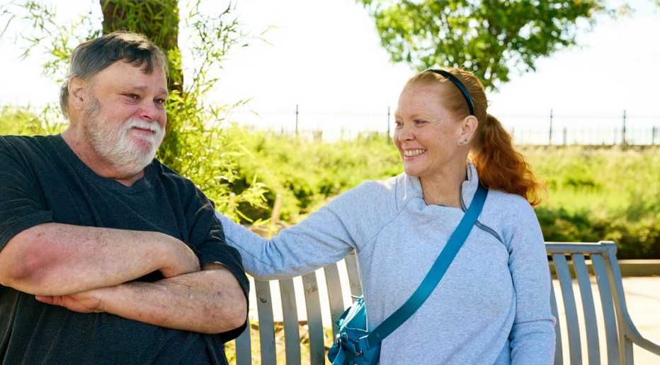 Woman sitting next to older man on a bench.