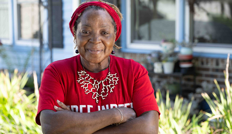 Johnnie Tisdale, African-American Black woman wearing red shirt and red headband standing outside