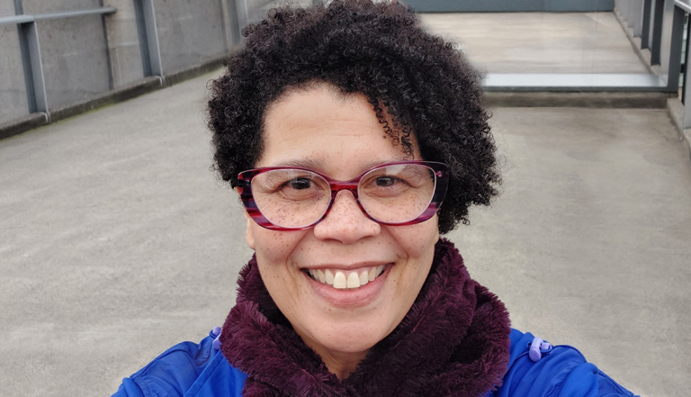 Older woman wearing glasses smiling on rooftop of building