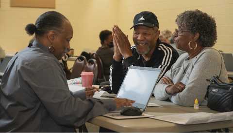 Photo of African American man smiling with his wife getting his taxes done at a site for free by AARP Foundation