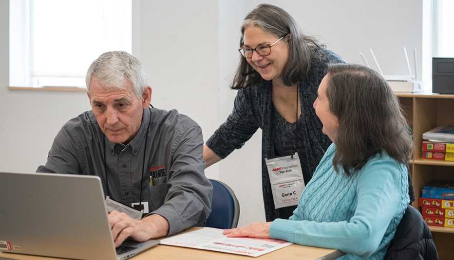 Gena Cadieux, AARP Foundation Tax-Aide volunteer, with another Tax-Aide volunteer man and female taxpayer wearing blue sweater