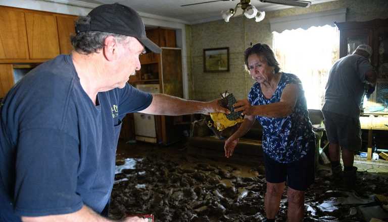 OLD FORT, NORTH CAROLINA - SEPTEMBER 29: Janice Whitley, right, hands her brother Terry Wilson some salvaged items while they remove valuables from their flooded home in the aftermath of Hurricane Helene on September 29, 2024 in Old Fort, North Carolina. According to reports, more than 60 people have been killed across the South due to the storm, and millions have been left without power. North Carolina has been approved for a Federal Major Disaster Declaration. (Photo by Melissa Sue Gerrits/Getty Images)