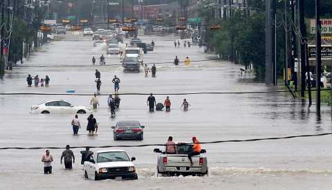 People walk through the flooded waters of Telephone Rd. in Houston on August 27, 2017 as the US fourth city city battles with tropical storm Harvey and resulting floods.