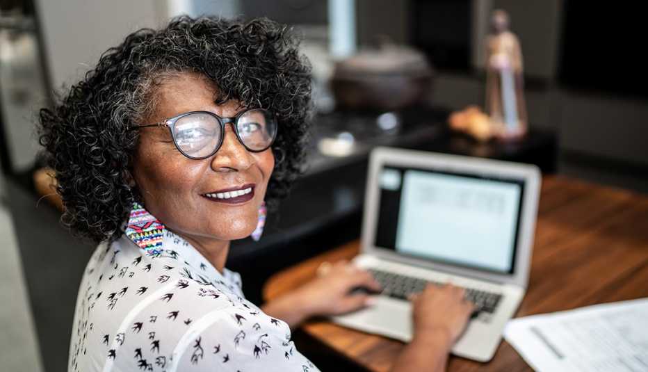 Smiling older woman working on a laptop at home.