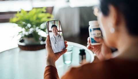 Senior Asian woman having a virtual appointment with doctor online, consulting her prescription and choice of medication on smartphone at home. Telemedicine, elderly and healthcare concept