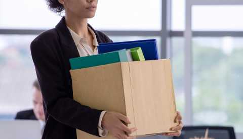 Business concept: An unemployed with her cardboard box walking out of the office