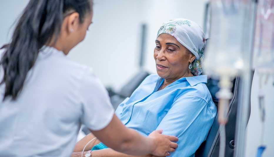 2024 SCP - Health Benefits A woman wearing a head scarf recovers from chemo treatment in the hospital. A doctor speaks with her and offers her support.