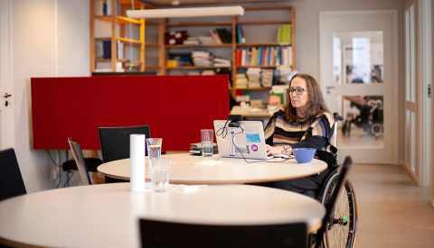 Senior woman in wheelchair working in office.