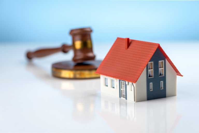 A judge hammer and a house on a blue background. Real estate law and house auction concepts