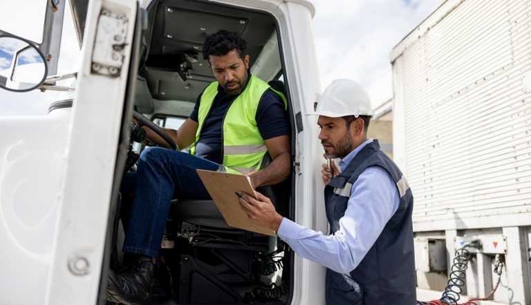 Foreperson talking to a truck driver while working at a distribution warehouse transporting merchandise - freight transportation concepts