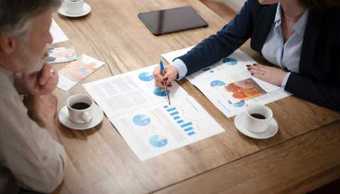 Senior man discussion with financial advisor while sitting at dining table in house.