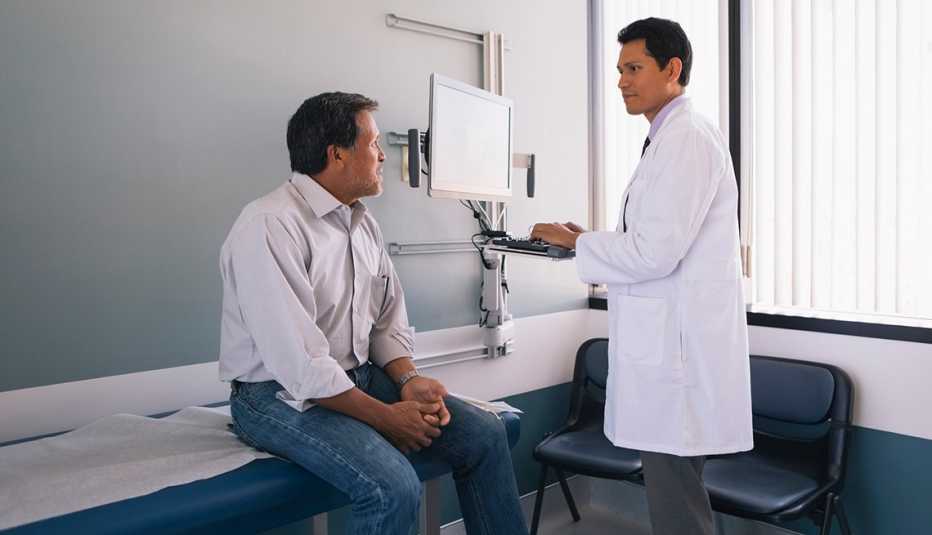 2025 SC Preview - Health Care Male doctor working on computer while discussing with senior male patient in hospital.