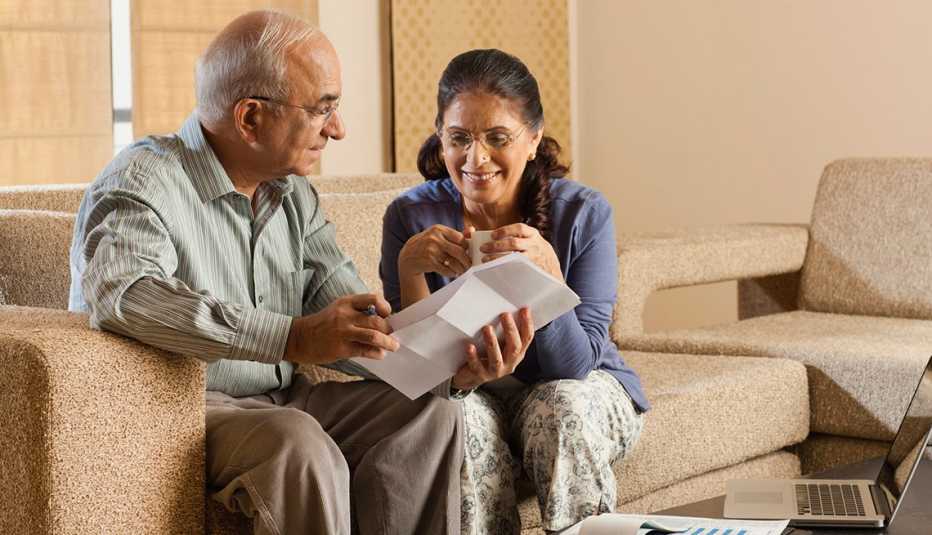 Senior couple working in living room, with laptop on coffee table
