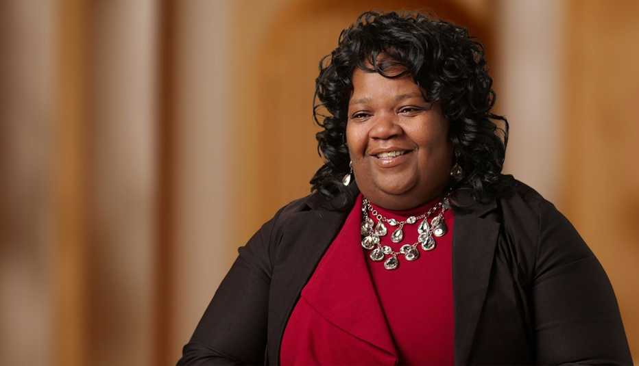 Margaret Bobb Margaret Bobb smiling and wearing a red outfit and black cardigan, bold necklace