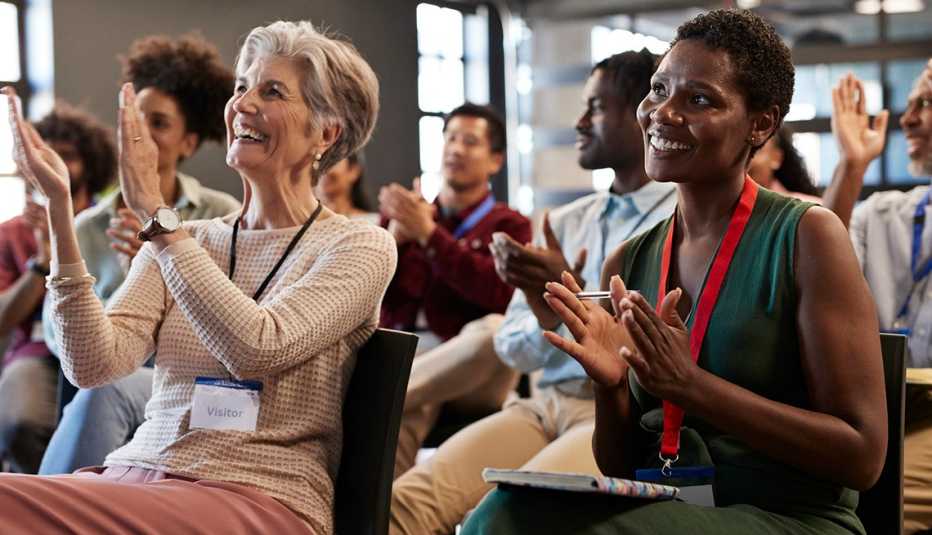 Happy female and male business colleagues clapping and applauding during seminar meeting in office