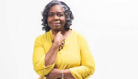 Photo of business owner Deborah Lofton posing in a yellow dress 